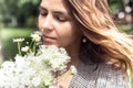 Portrait closeup of young charming woman smelling and enjoying aroma of bouquet plucked white wild flowers. Walking in Royalty Free Stock Photo