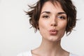 Portrait closeup of young woman with short brown hair in basic t-shirt making kiss face at camera Royalty Free Stock Photo