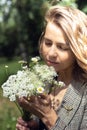 Portrait closeup of young woman smelling with closed eyes and enjoying aroma of bouquet plucked white wild flowers Royalty Free Stock Photo