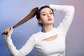 Portrait of cocky teenager girl with long ponytail hair on studio background, young woman with rebellious character, fashion model