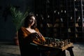 Portrait of cofident young business woman wearing elegant eyeglasses making chess move sitting in armchair in dark Royalty Free Stock Photo