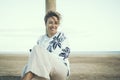 Portrait in cold tones mood of young adult female people smiling and enjoying outdoor leisure activity alone. Beach and ocean view Royalty Free Stock Photo