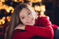 Portrait of comfy sitting at home young lady wearing red jumper folded hands hug herself sitting in divan isolated xmas Royalty Free Stock Photo