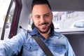 Portrait of commuter student man smiling and using taxi cab service in back seat of car. Concept of commute, transport service, m Royalty Free Stock Photo