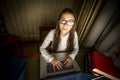 Portrait of computer geek girl sitting at laptop at night