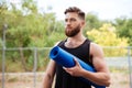 Portrait of a concentrated bearded sports man holding yoga mat