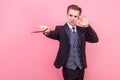 Portrait of concentrated focused magician raising magic wand, using mental power to perform trick. on pink background