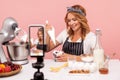 Portrait of concentrated food vlogger showing process of decoration desserts in live stream, sitting in front of smart phone on