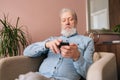 Portrait of concentrated handsome mature male holding smartphone using mobile online app, looking to screen sitting on Royalty Free Stock Photo