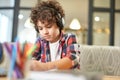 Portrait of concentrated hispanic school boy wearing headphones, preparing homework while sitting at the desk at home Royalty Free Stock Photo