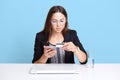 Portrait of concentrated professional business woman using mobile phone and credit card at her work, sitting at white desk, making Royalty Free Stock Photo