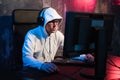 Portrait of concentrated young man in glasses and headset in dark room playing online computer game or competing in