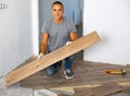 Portrait of concentrated young man in ordinary clothes installing new wooden laminate flooring Royalty Free Stock Photo