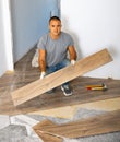 Portrait of concentrated young man in ordinary clothes installing new wooden laminate flooring Royalty Free Stock Photo