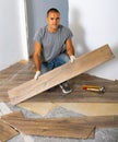 Portrait of concentrated young man in ordinary clothes installing new wooden laminate flooring Royalty Free Stock Photo