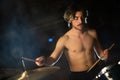 Portrait of concentrated young man playing shirtless on drum set