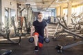 Portrait of concentration young adult man handsome athlete working out in gym, standing on the knees and holding two dumbbells, Royalty Free Stock Photo