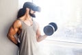 Portrait of concentration young adult sport man with long curly hair training in gym, holding one dumbbell with raised arm, doing Royalty Free Stock Photo