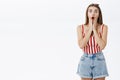 Portrait of concerned shocked and worried troubled cute woman in striped top and shorts dropping jaw touching face with