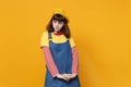 Portrait of concerned upset girl teenager in french beret, denim sundress looking aside isolated on yellow wall