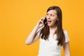 Portrait of concerned young girl in white casual clothes looking aside talking on mobile phone isolated on bright yellow Royalty Free Stock Photo