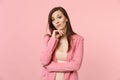 Portrait of concerned young woman wearing jacket put hand prop up on chin looking camera on pastel pink