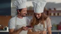 Portrait of confectioners decorating dessert with cherry on kitchen