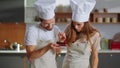 Portrait of confectioners decorating dessert with cherry on kitchen