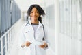 Portrait confident African American female doctor medical professional writing patient notes isolated on hospital clinic hallway