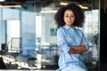 Portrait of a confident African-American young business woman sitting in the office at the desk, hands crossed and Royalty Free Stock Photo