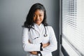 Portrait confident African female doctor medical professional writing patient notes isolated on hospital clinic hallway