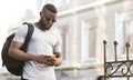 Portrait of confident african man with backpack textmessaging Royalty Free Stock Photo