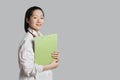 Portrait of a confident Asian female doctor holding clipboard over gray background Royalty Free Stock Photo