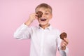 Portrait of confident attractive little boy holds american chocolate chip cookies on the eyse, dressed white stylish shirt