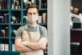 Portrait of confident barber posing in protective mask and apron in beauty salon interior, empty space