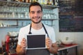Portrait of confident barista holding blank chalkboard