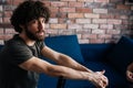 Portrait of confident bearded young man looking at camera sitting on chair and holding to chairbac in cozy living room Royalty Free Stock Photo