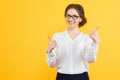 Portrait of confident beautiful young smiling happy business woman with thumbs up on yellow background Royalty Free Stock Photo