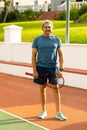 Portrait of confident biracial senior man holding tennis racket while standing in tennis court Royalty Free Stock Photo