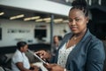 Portrait of a confident black businesswoman using her tablet looking into the camera with all african american team in the Royalty Free Stock Photo