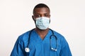 Portrait of confident black doctor in face mask over white