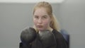 Portrait of confident blond woman in boxing gloves imitating dodging blows in the gym close up. Cute newbie kickboxer