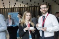 Portrait of confident business people holding coffee cups at lobby in convention center Royalty Free Stock Photo