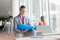 Portrait of confident businessman holding file while sitting at lobby in convention center Royalty Free Stock Photo