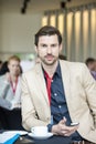 Portrait of confident businessman holding smart phone while sitting at convention center Royalty Free Stock Photo