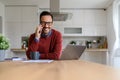 Portrait of confident businessman making business call over cellphone while using laptop at home Royalty Free Stock Photo