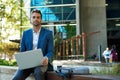 Confident businessman sitting outside his office building using a laptop Royalty Free Stock Photo