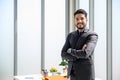 Portrait of confident businessman smiling happy standing in front of a desk with arms crossed at the office. launching ideas onto Royalty Free Stock Photo