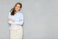 Confident businesswoman standing against wall with crossed arms