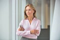Portrait of confident businesswoman standing with arms crossed in corridor at office Royalty Free Stock Photo